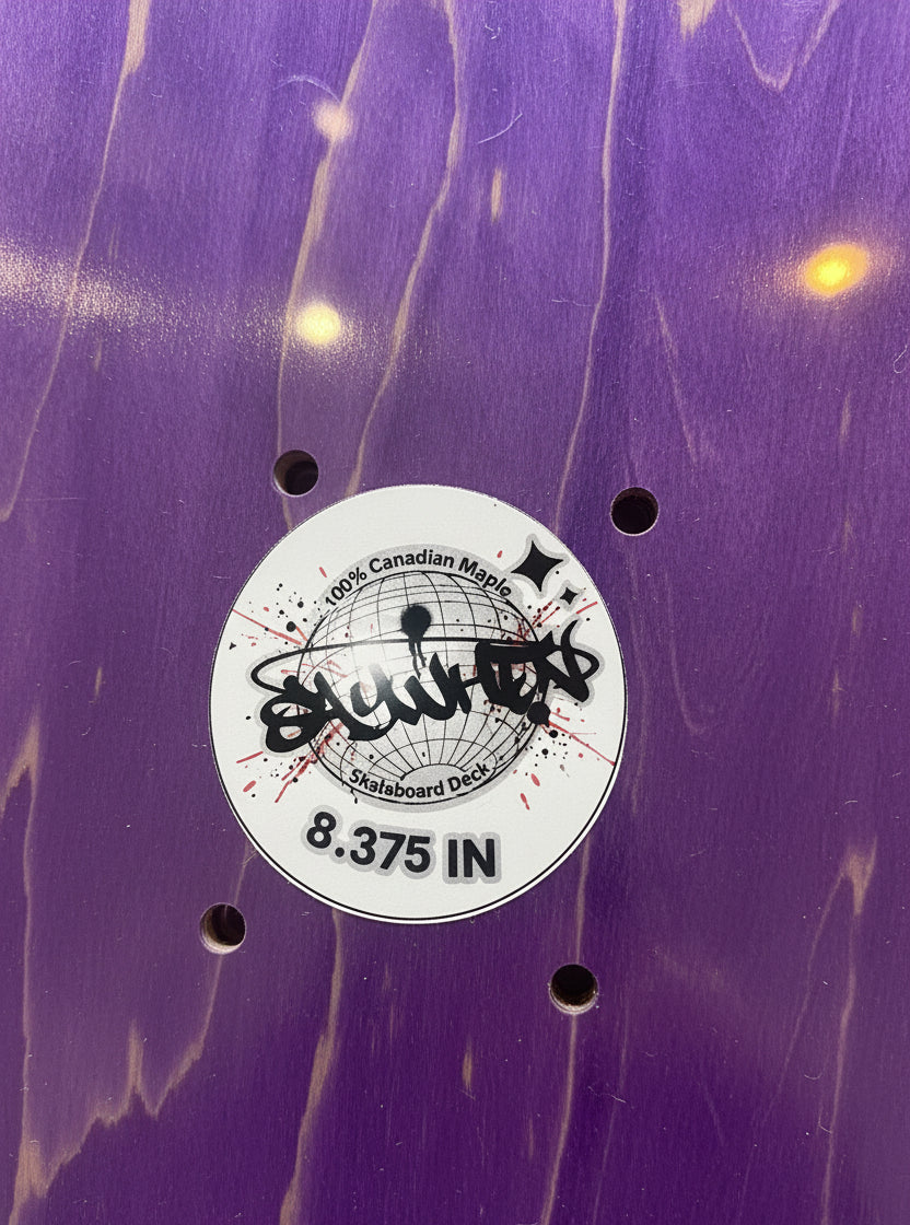 Close-up of a purple wood grain skateboard deck with a white circular sticker in the center reading Say When