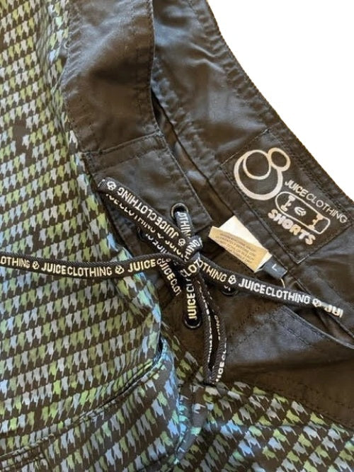 Close-up of a Juicy Clothing shorts garment showing the inner waistband, black drawstring with white logo text, and a green, gray, and black houndstooth pattern.