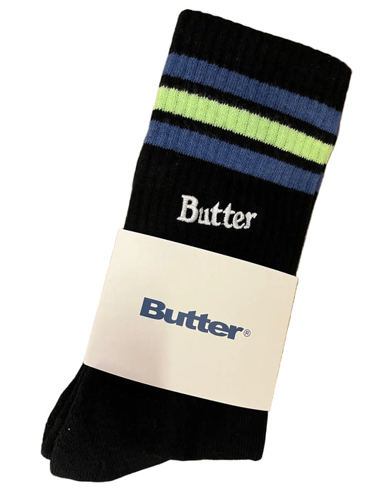 Black sock with blue and green stripes and 'Butter' branding on a wooden surface