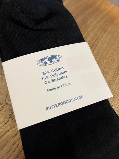 Black sock with a label showing fabric composition and brand information on a wooden surface