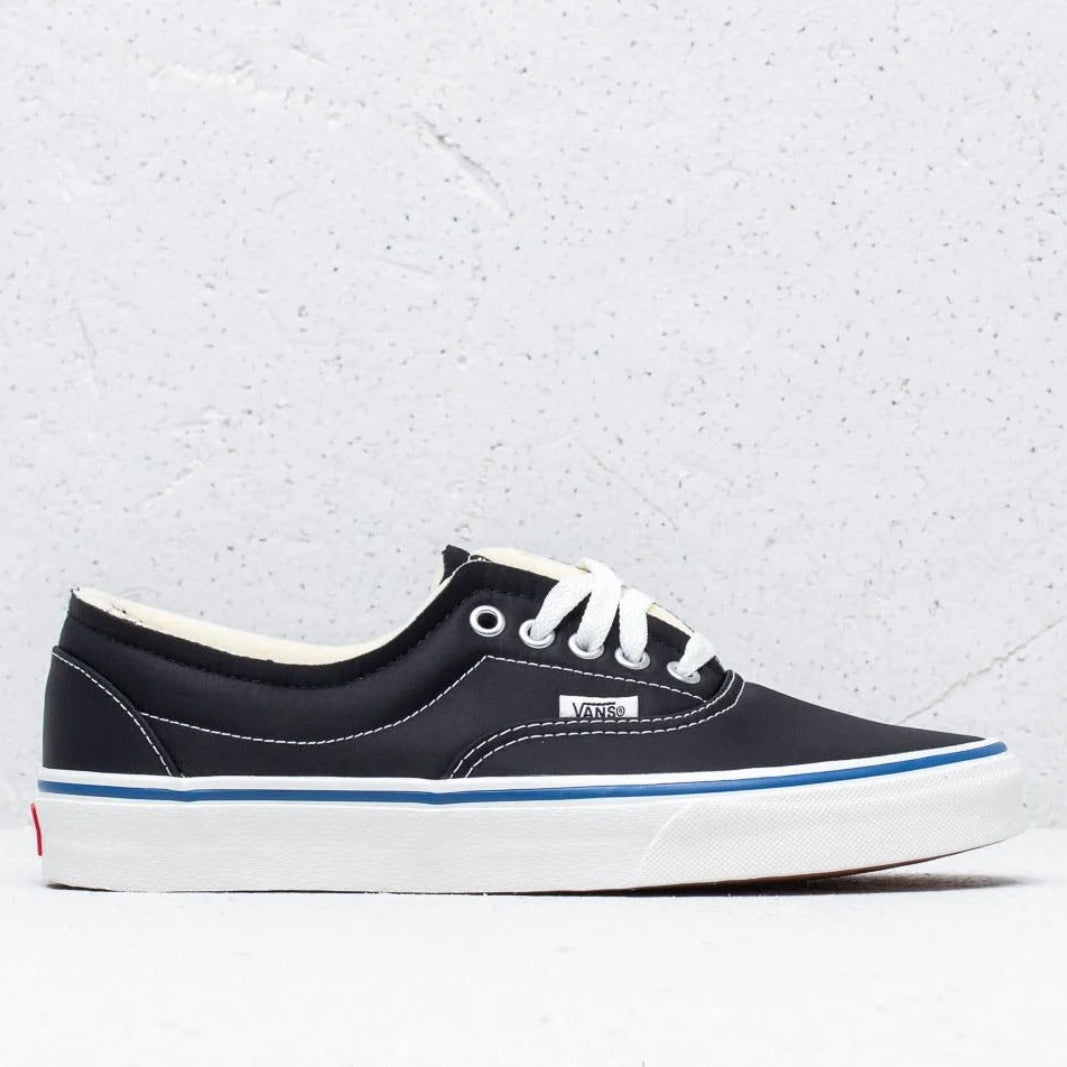 A single Vans sneaker in navy blue canvas with white laces, a thick white platform sole, and a thin blue stripe, shown against a light gray textured background.