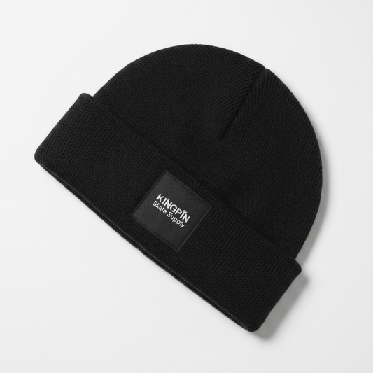 A black fitted beanie with a label on the side, that reads 'KINGPIN' on the first line and 'Skate Supply' underneath. 