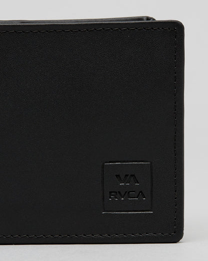 Close-up of a black leather bi-fold wallet showing the corner, black stitching, and an embossed square logo patch with 'VA RVCA' on a light gray background. cedar bifold