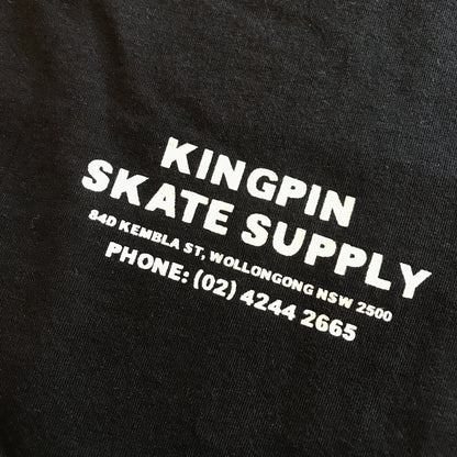 Close-up of a black fabric surface with bold white printed text reading 'KINGPIN SKATE SUPPLY' and smaller address and phone details.