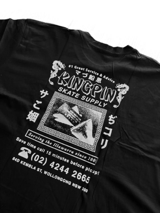 A black short-sleeve T-shirt laid flat on a white background, showing a large white graphic print on the back. The graphic features the words 'KINGPIN SKATE SUPPLY,' Japanese text, a vintage-style storefront sign illustration, and a phone number.