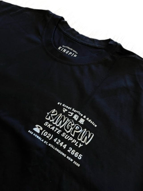 A close-up of a black t-shirt featuring white printed graphics and text on the front, including 'KINGPIN SKATE SUPPLY' and Japanese characters, with the brand 'KINGPIN' visible inside the collar.