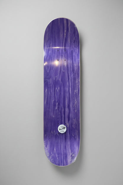 A purple skateboard deck with a glossy woodgrain finish and a small circular sticker near the bottom, shown against a neutral gray background.
