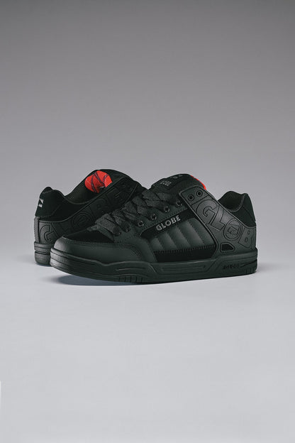 globe tilt skate shoes Black sneakers with red accents on a gray background