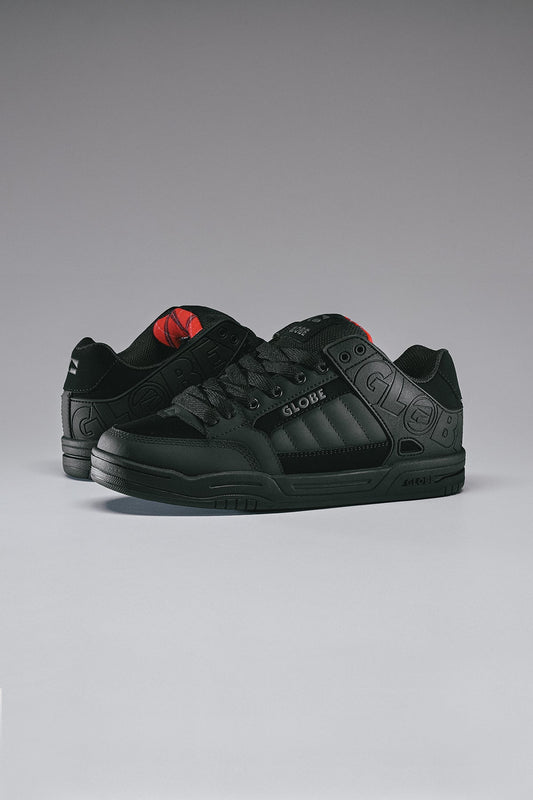 globe tilt skate shoes Black sneakers with red accents on a gray background