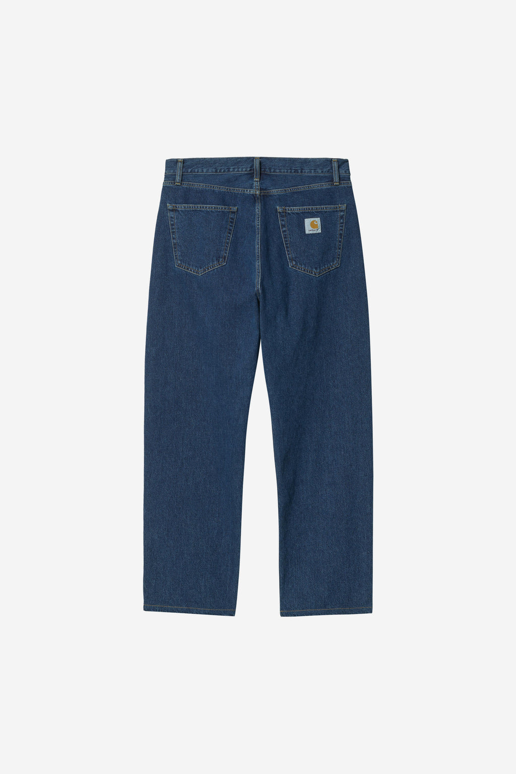 Back view of a pair of dark blue denim jeans on a light gray background, showing the back pockets and a small Carhartt logo patch on the right pocket.