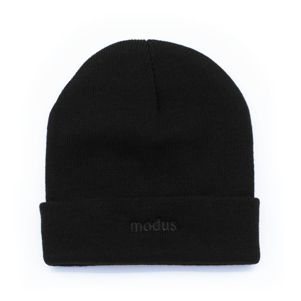 A black knit beanie hat with a folded cuff, featuring the word 'modus.' embroidered in dark gray on the front cuff, set against a plain white background.