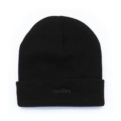 A black knit beanie hat with a folded cuff, featuring the word 'modus.' embroidered in dark gray on the front cuff, set against a plain white background.