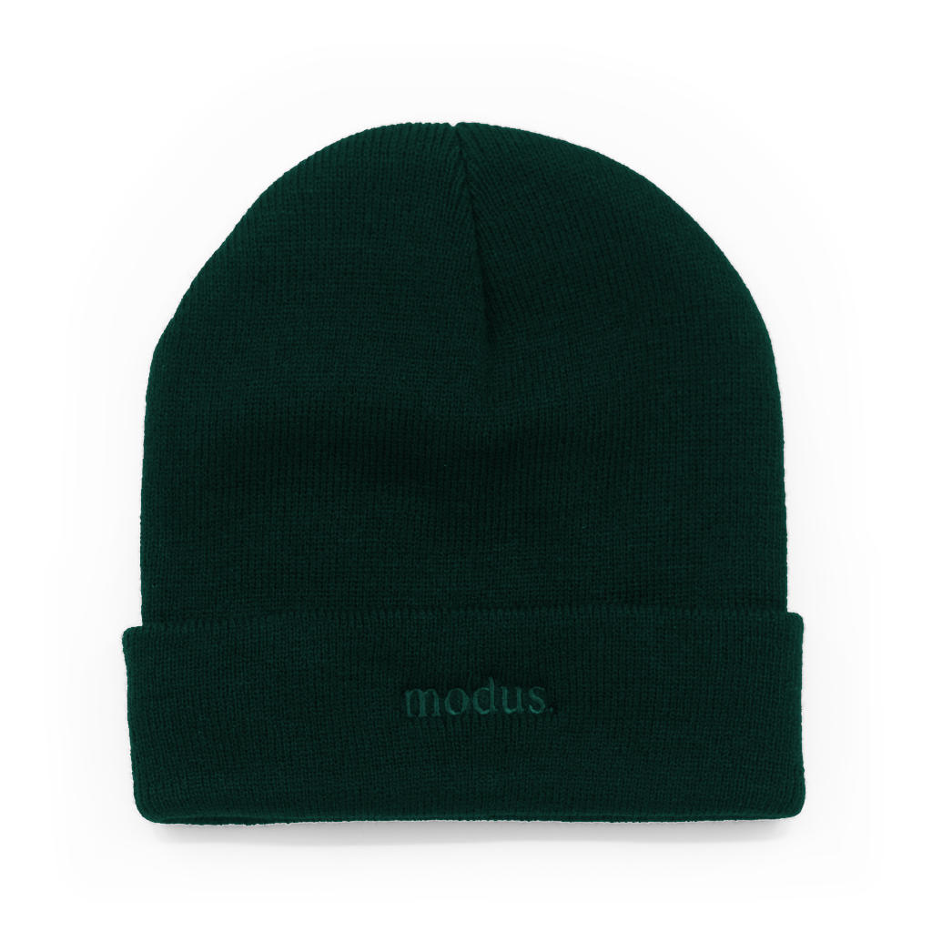 A dark forest green knit beanie with a folded cuff, featuring the word 'modus.' embroidered in matching green on the front cuff, set against a plain white background.