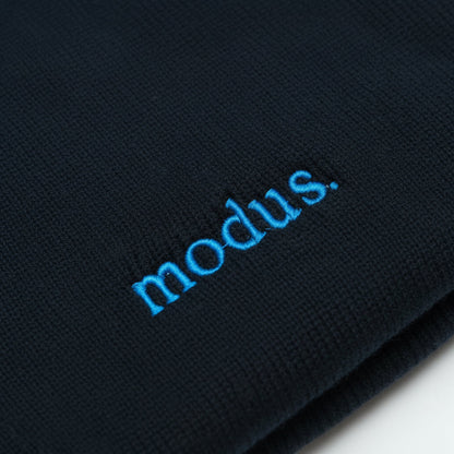 A dark navy blue knit beanie with the word 'modus.' embroidered in light blue on the front cuff, shown against a plain white background.