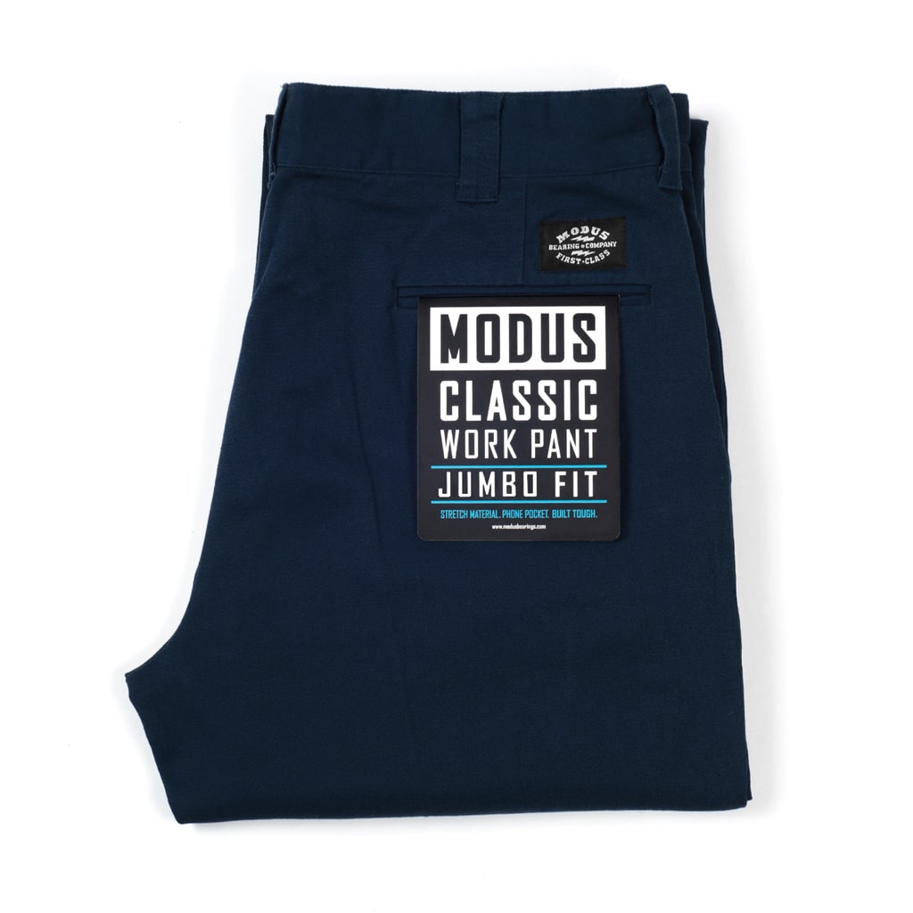 A folded pair of dark navy blue work pants with a prominent black and white 'Modus Classic Work Pant Jumbo Fit' label on the back pocket, set against a plain white background.