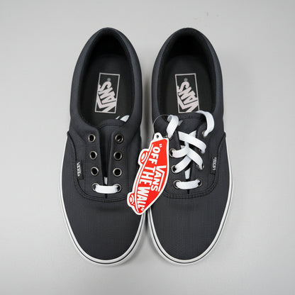 A pair of black Vans era sneakers with white laces and a red 'Off The Wall' hangtag, photographed from above on a concrete floor.