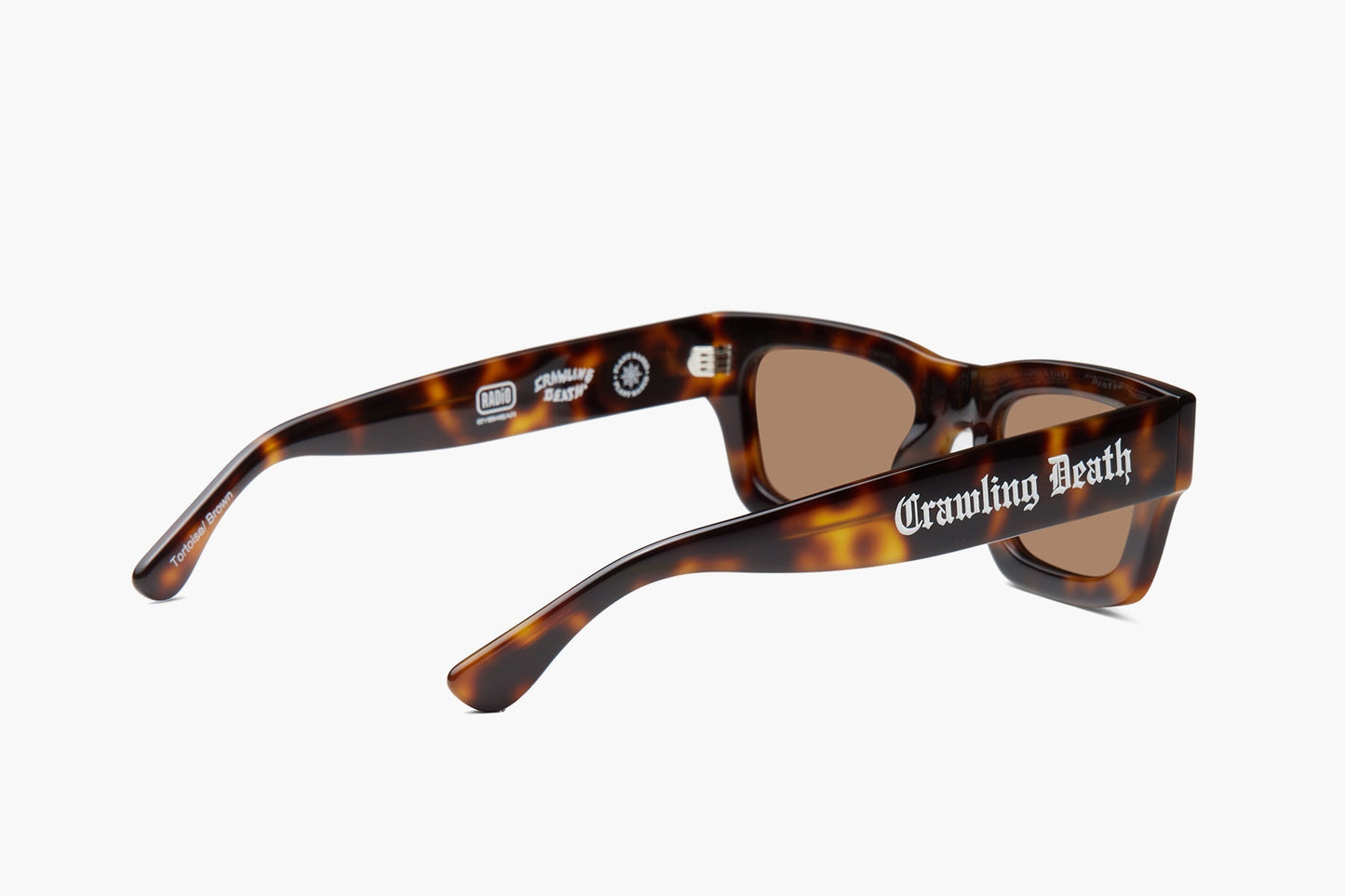 Tortoiseshell sunglasses with brown lenses and the words 'Crawling Beast' printed in white on the side, shown on a light gray background.