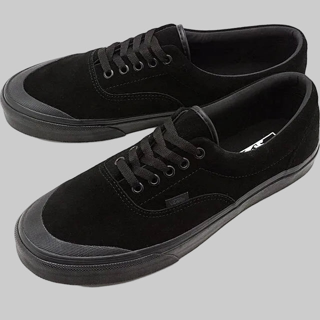A pair of black suede low-top sneakers with black laces, black rubber toe caps, and black Vans side tabs, displayed on a clean white background.