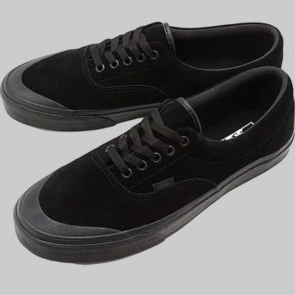 A pair of black suede low-top sneakers with black laces, black rubber toe caps, and black Vans side tabs, displayed on a clean white background.