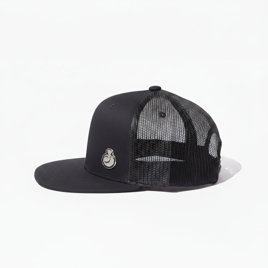 A juice clothing black trucker-style snapback cap with a structured flat brim, black mesh back panels, and a small silver circular logo on the front panel, shown against a plain white background.