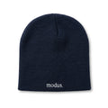 A dark navy blue knit beanie with the word 'modus.' embroidered in white on the cuff, resting on a light brown wooden surface.