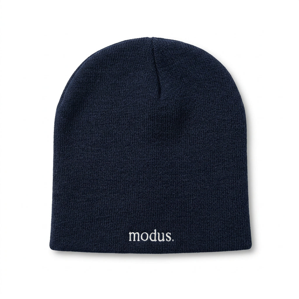 A dark navy blue knit beanie with the word 'modus.' embroidered in white on the cuff, resting on a light brown wooden surface.