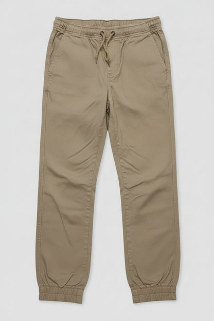 A pair of kingpin slim fit khaki chino pants with an elastic waist and drawstring, and elastic cuff ankles lay flat.